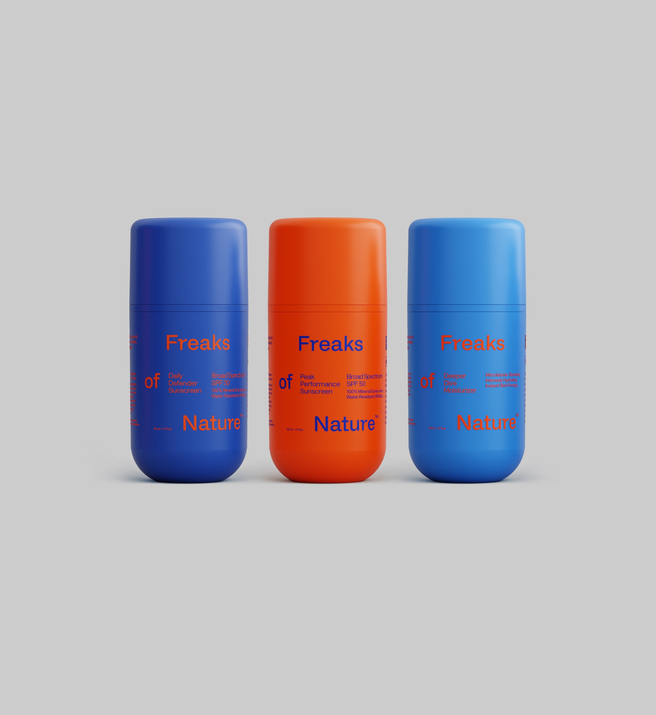 Three cylindrical deodorant bottles from the Freaks of Nature Skincare brand are displayed against a gray background. From left to right, the colors are blue, orange, and light blue. Each bottle from the Freak Trio collection is labeled with red text "Freaks of Nature," reminiscent of high-quality products like Peak Performance SPF50 Sunscreen.