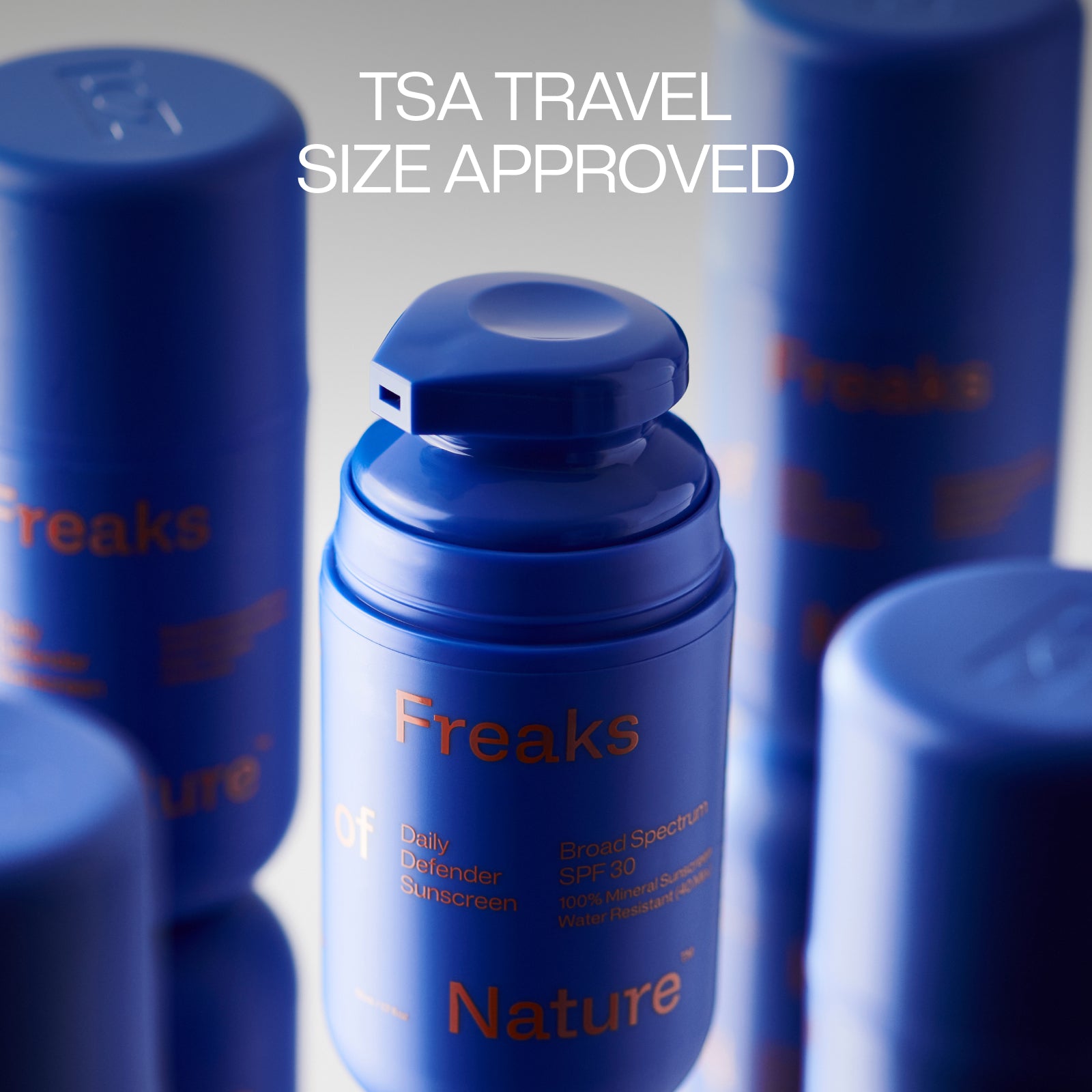 Blue bottles of "Freaks of Nature Skincare" Daily Defender SPF30 Sunscreen are shown. The text "TSA TRAVEL SIZE APPROVED" is displayed above the bottles, emphasizing its vegan squalane-infused formula perfect for carry-on essentials.