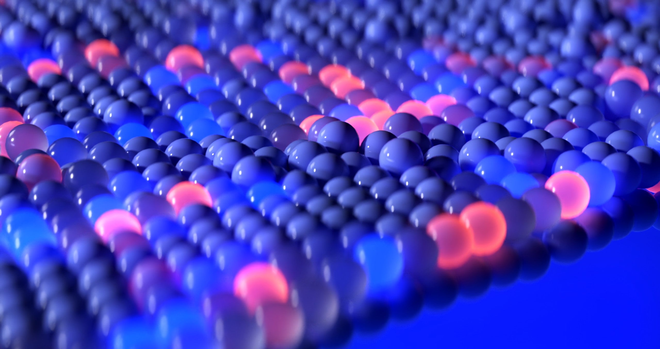An abstract image featuring a close-up view of numerous small, spherical beads arranged in a grid. The beads are primarily blue, with some glowing in shades of pink and orange, creating a visually striking contrast. The background is blue, enhancing the vibrant colors.